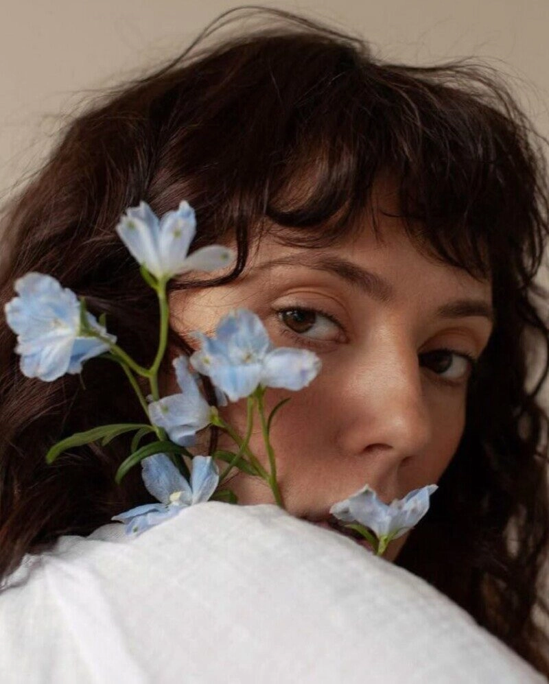 ảnh cô gái cầm hoa che mặt buồn